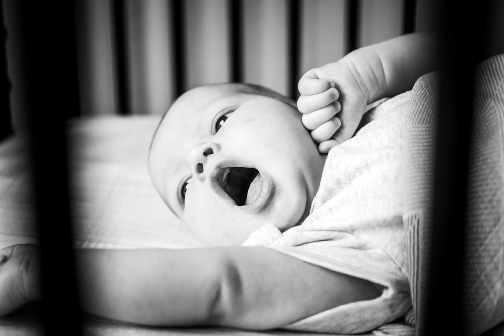 black and white photo of Dallas newborn baby yawning in crib