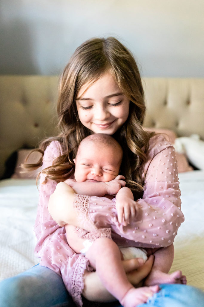 big sister holding baby by plano newborn photographer